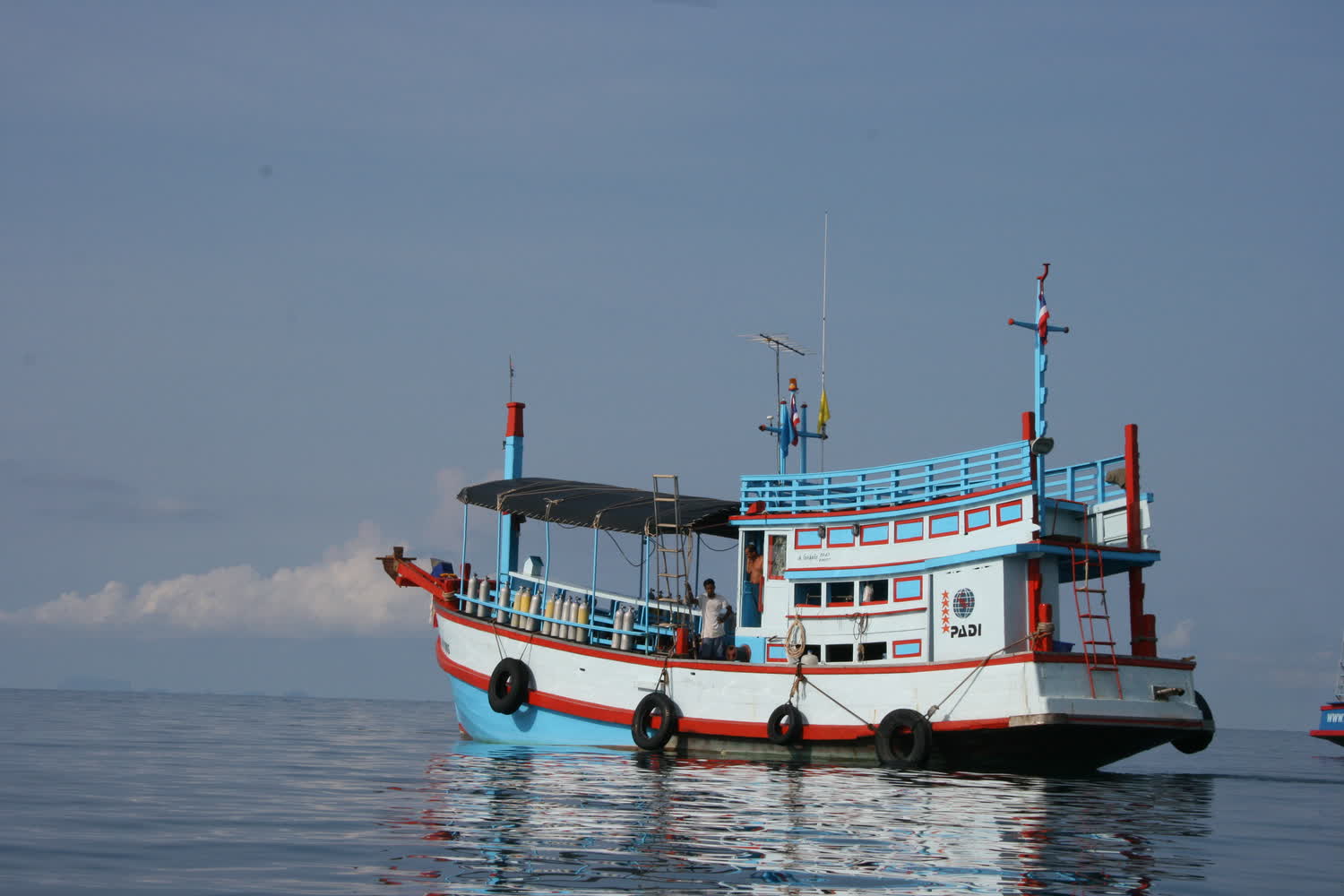 A wooden dive boat moored off Koh Tao, gear laid out on deck before a morning of dives